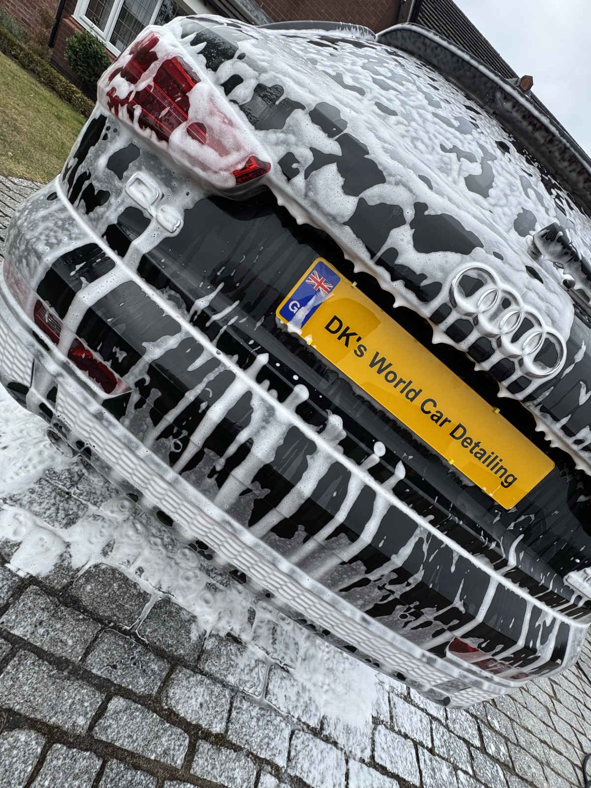 Close-up of an Audi's snow-foamed rear bumper and badge during a mobile valet in Prescot
